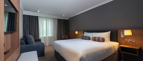Una habitación de hotel con una cama grande, un sofá, un televisor y un escritorio.