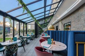 An indoor dining area with tables and chairs, a glass ceiling, and a stone wall. - Clybaun Hotel Galway (Galway)