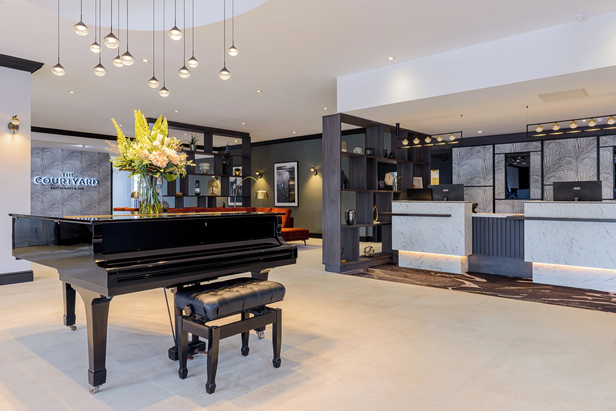 A modern interior with a grand piano, a reception desk, and a wall-mounted display.