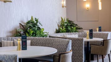 Ein Restaurant mit runden Tischen, gepolsterten Sitzplätzen, einer Weinkarte und Wandleuchten.