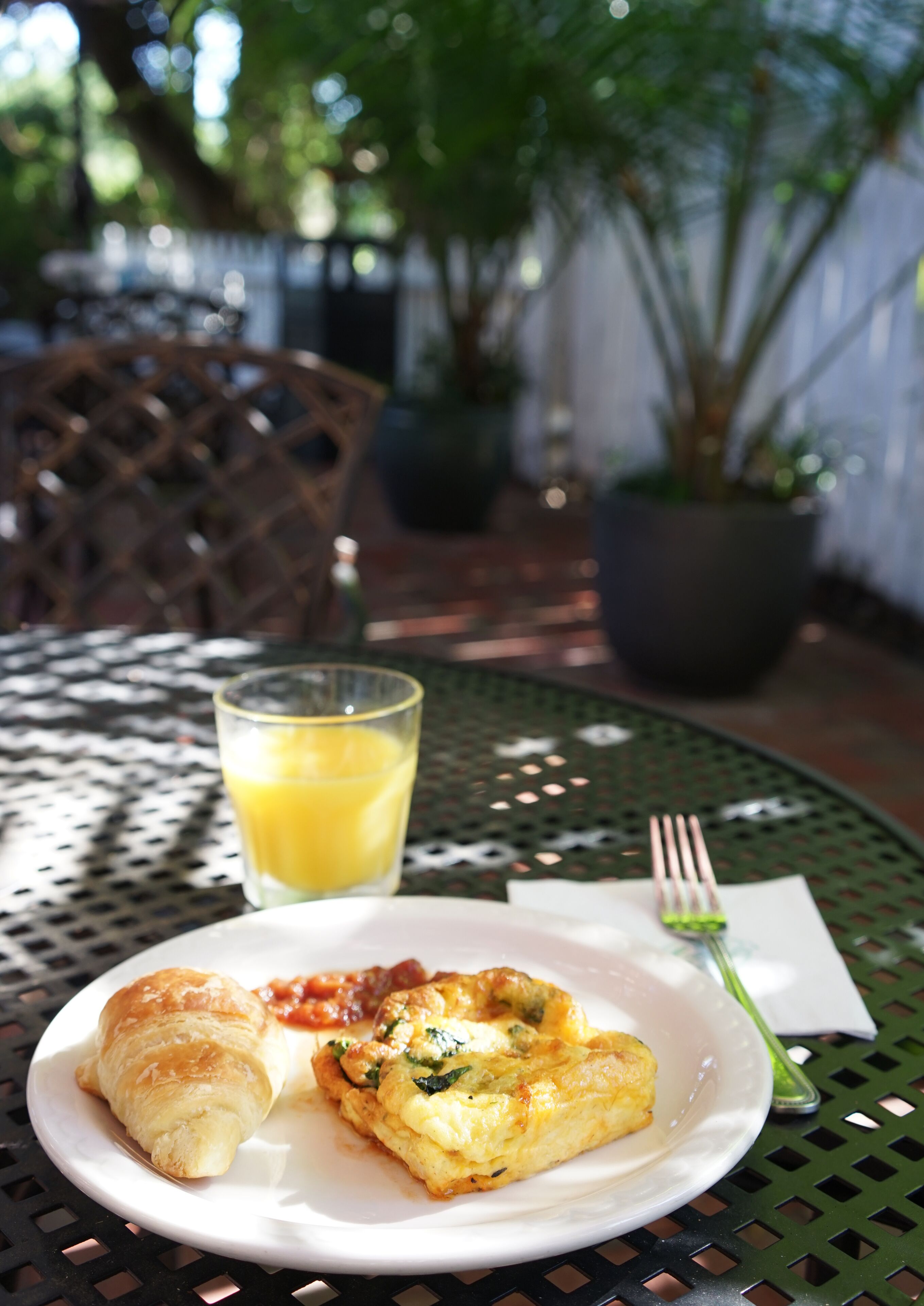 A plate with food and a glass of orange juice on a table outdoors.