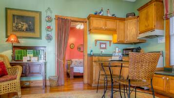 A cozy kitchen with wooden cabinets, a dining area with wicker chairs, and a small table.