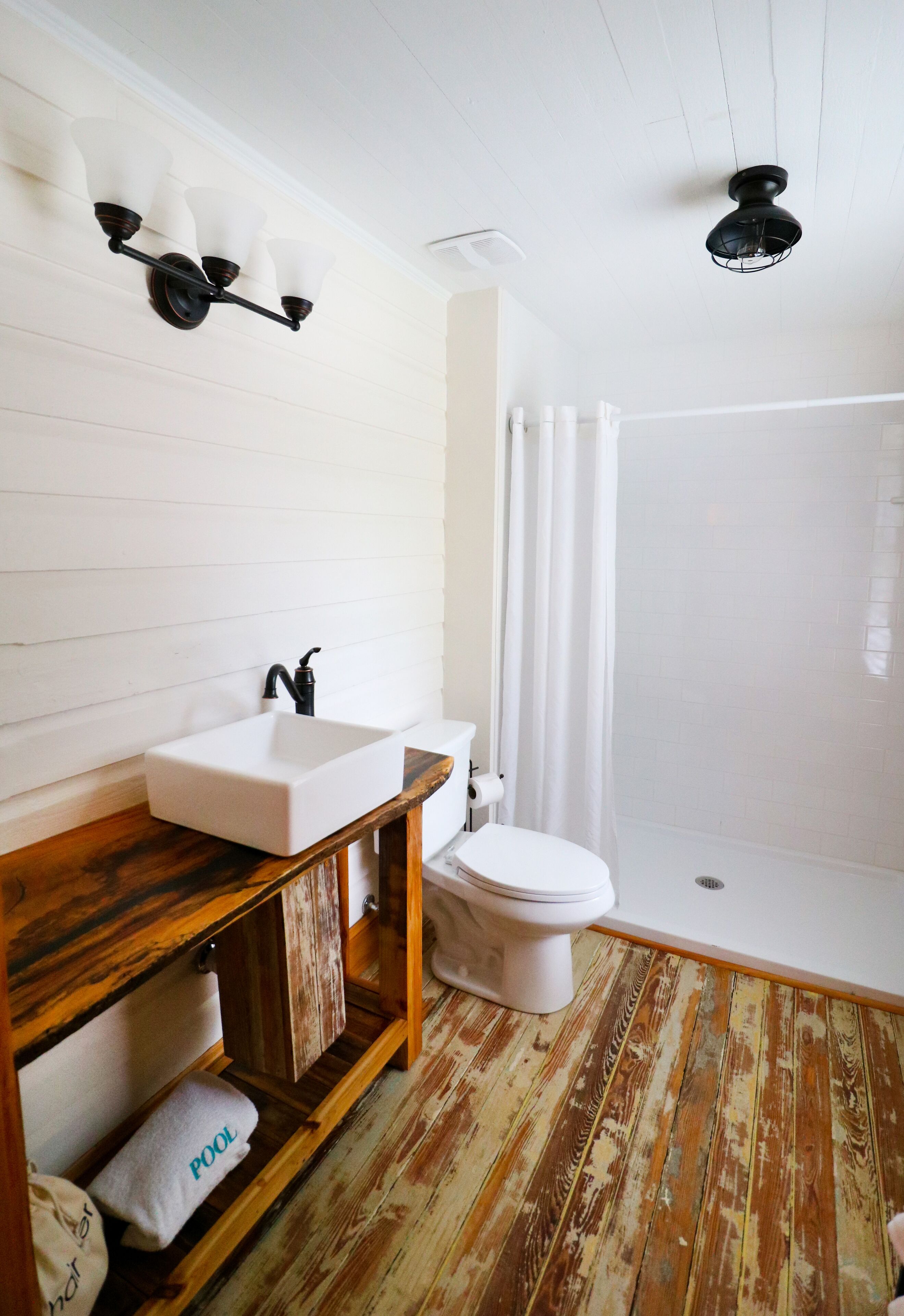 A bathroom with a wooden vanity, white sink, and toilet.