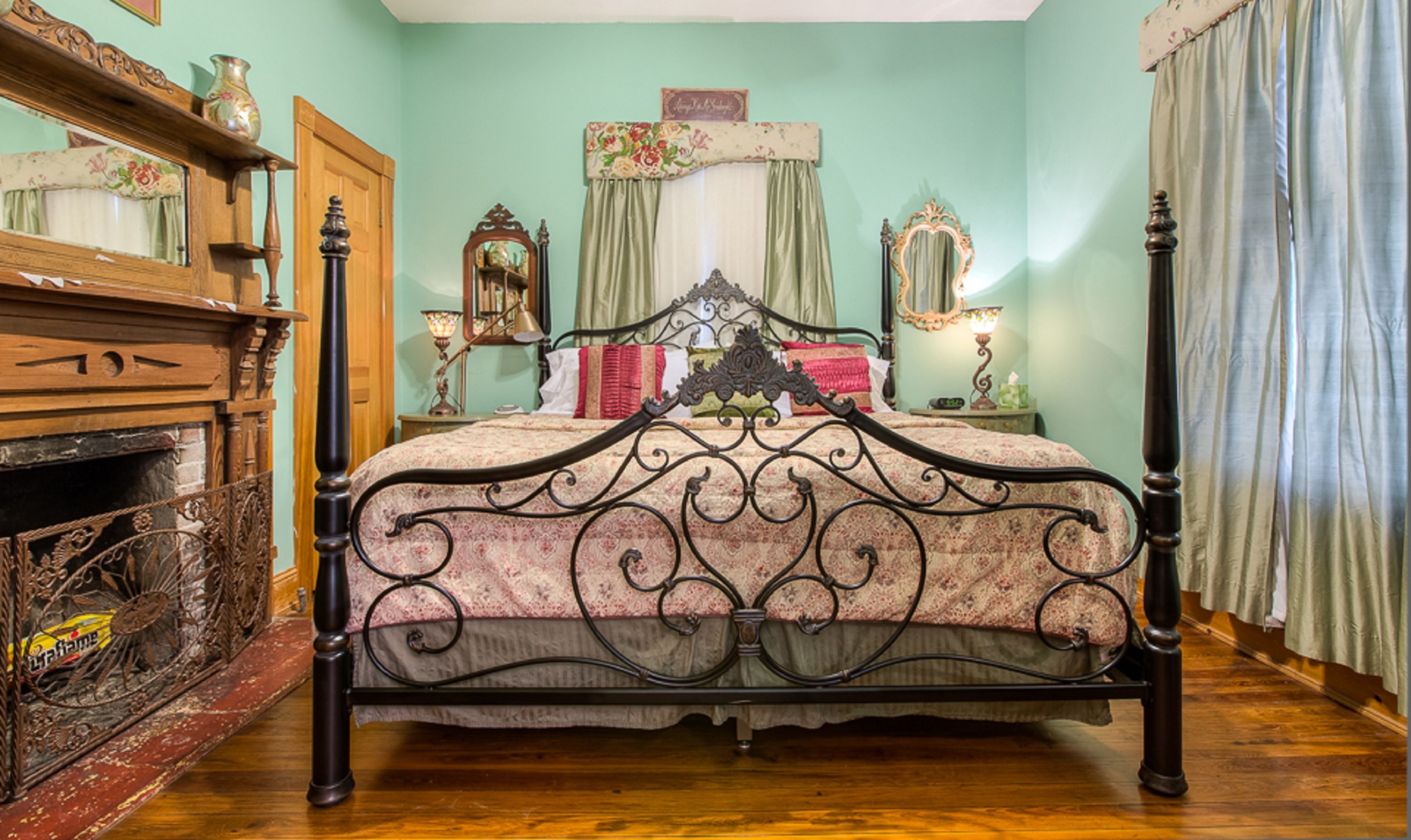 Ein traditionelles Himmelbett mit aufwendiger Metallverzierung, eine Holzkommode mit Spiegel und ein Kopfstück mit Blumenmuster.