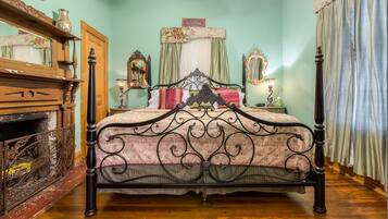 Ein traditionelles Himmelbett mit aufwendiger Metallverzierung, eine Holzkommode mit Spiegel und ein Kopfstück mit Blumenmuster.