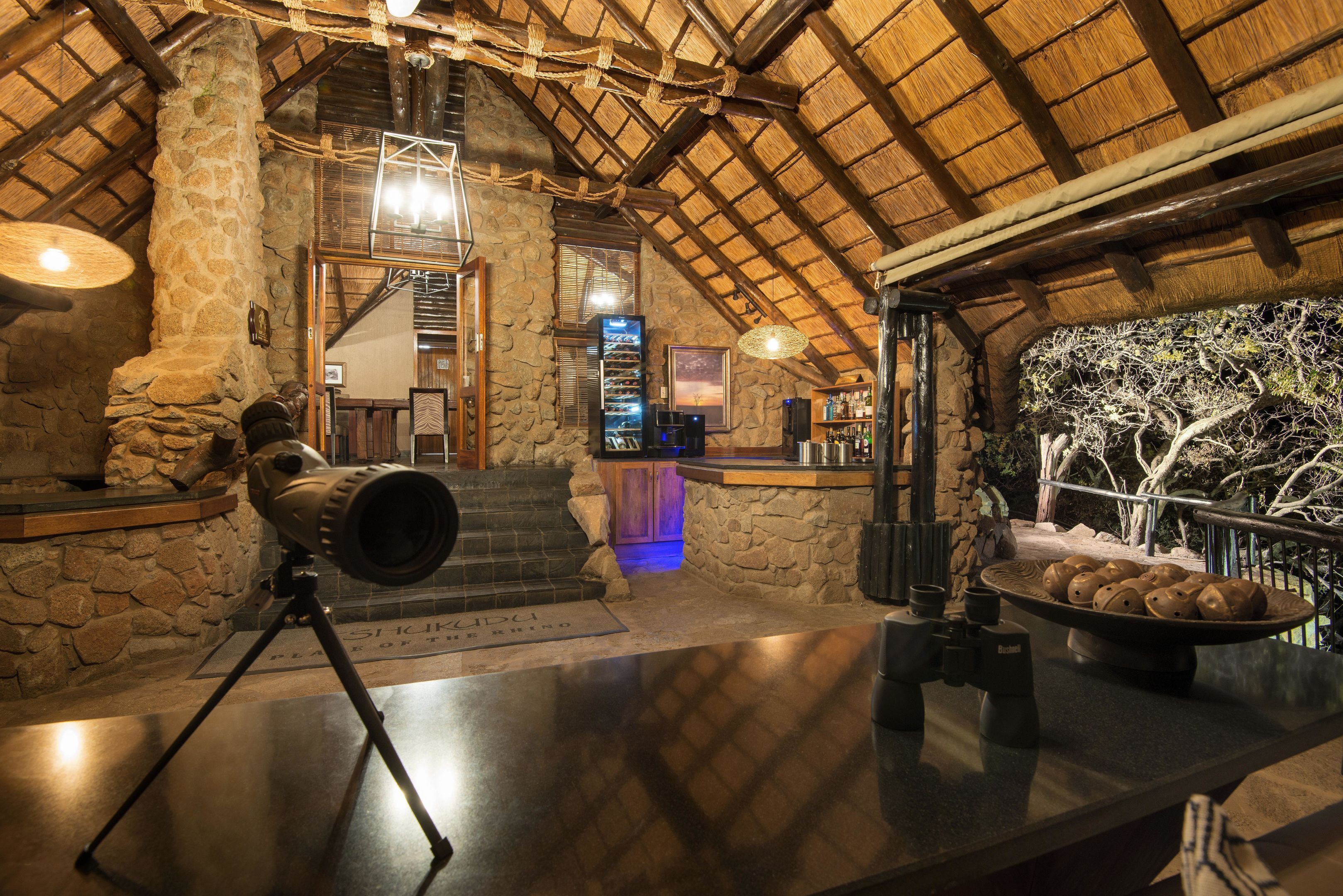 A rustic interior with stone walls, a wooden ceiling, and a telescope on a tripod.