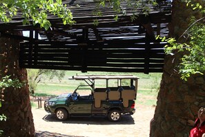 A green SUV parked under a wooden pergola with stone pillars. - Tshukudu Bush Lodge (Pilanesberg National Park)