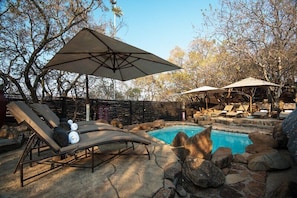 Una piscina al aire libre, sombrillas, tumbonas