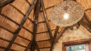 A rustic kitchen with a thatched ceiling, wooden cabinets, and a large window. - Tshukudu Bush Lodge (Pilanesberg National Park)