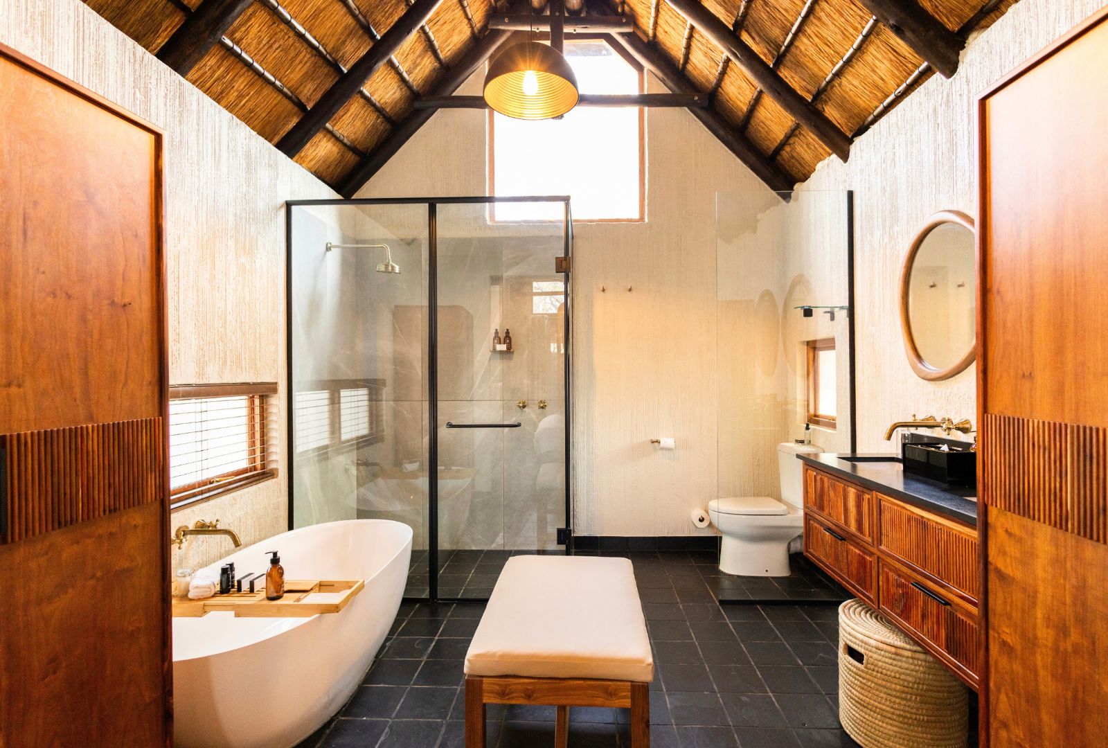 A modern bathroom with a glass shower enclosure, a freestanding bathtub, and a wooden vanity.