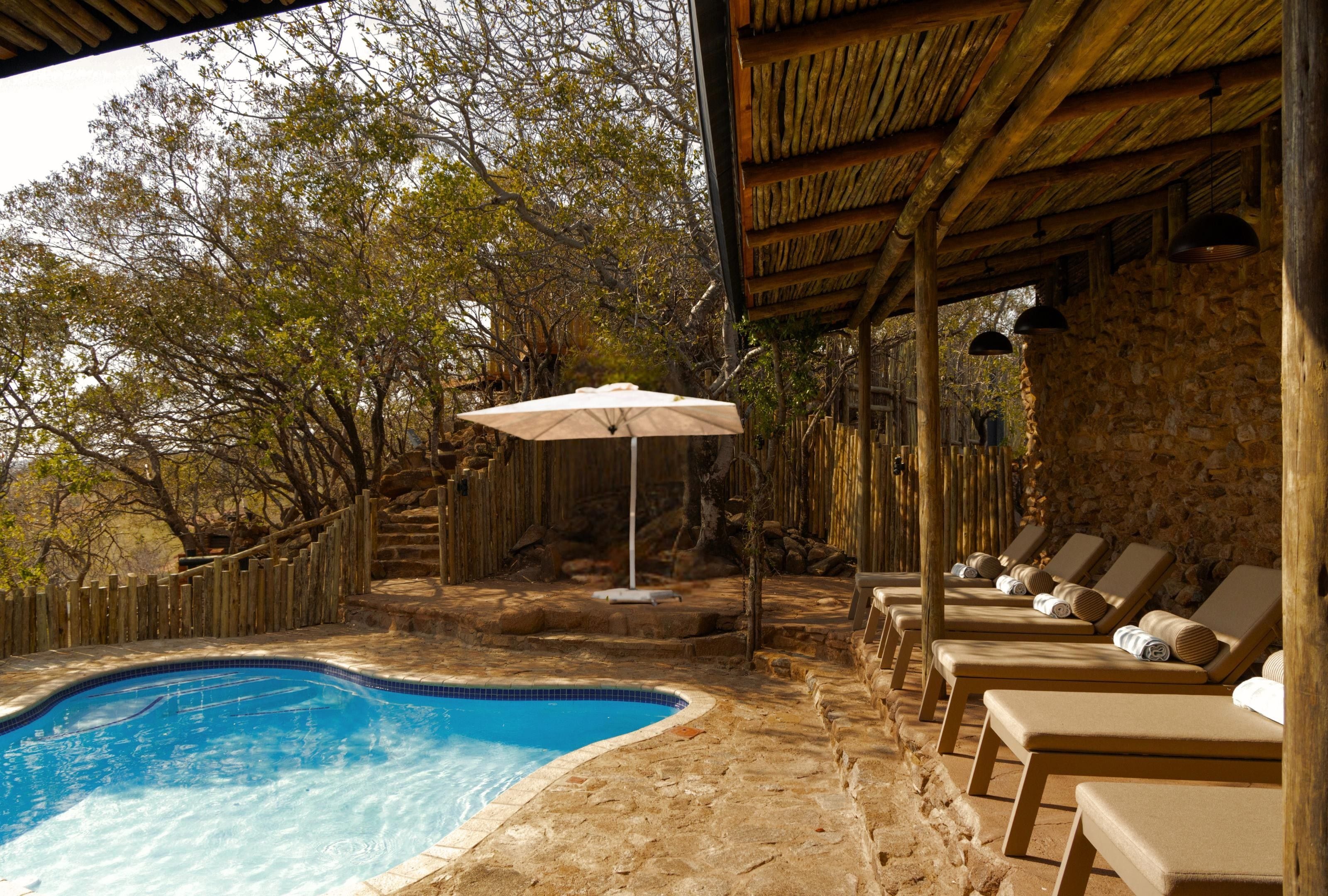 Uma área de piscina com espreguiçadeiras e uma pérgula de madeira.