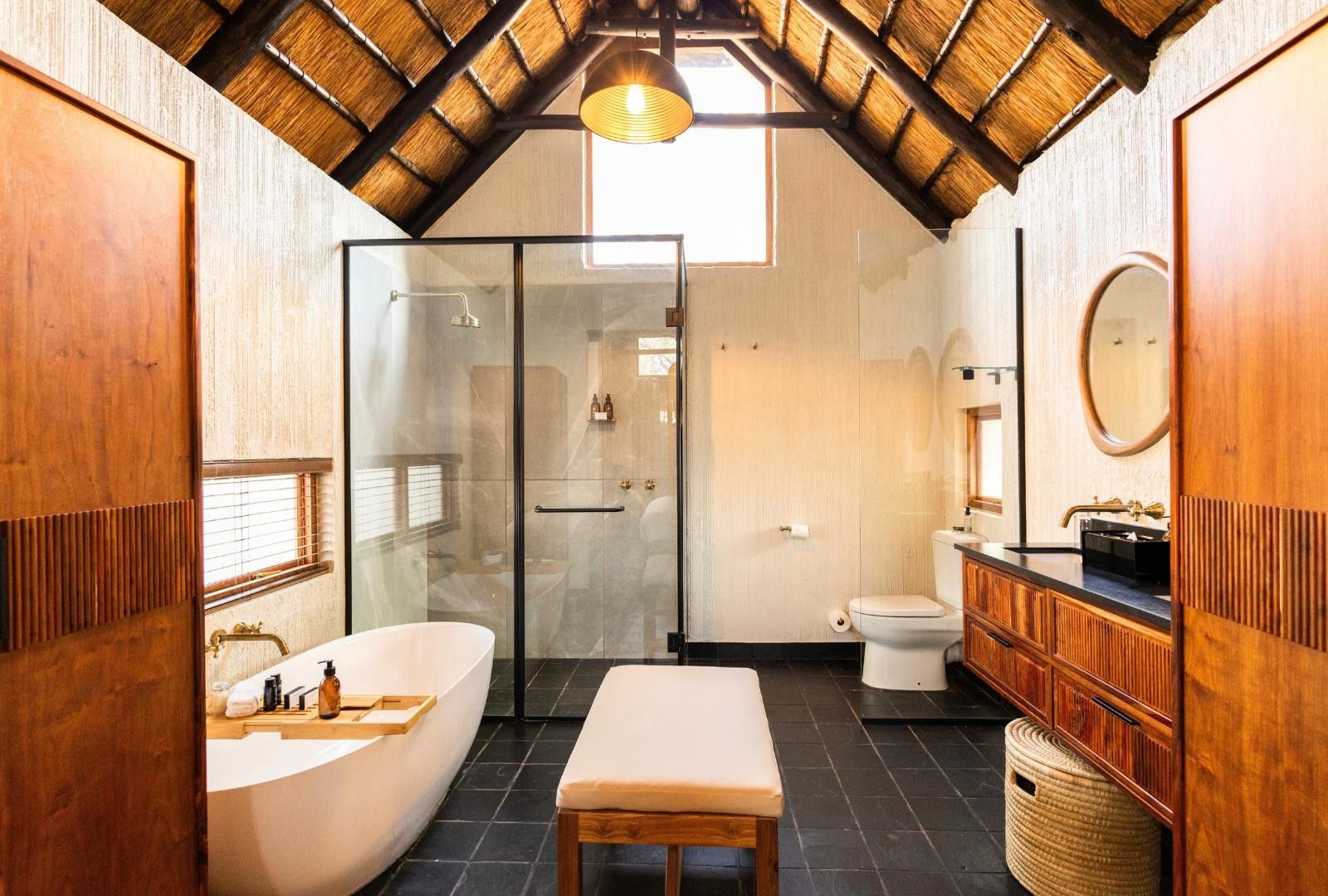 Uma casa de banho moderna com uma banheira grande, um chuveiro com parede de vidro, sanita e espelho sobre a pia.