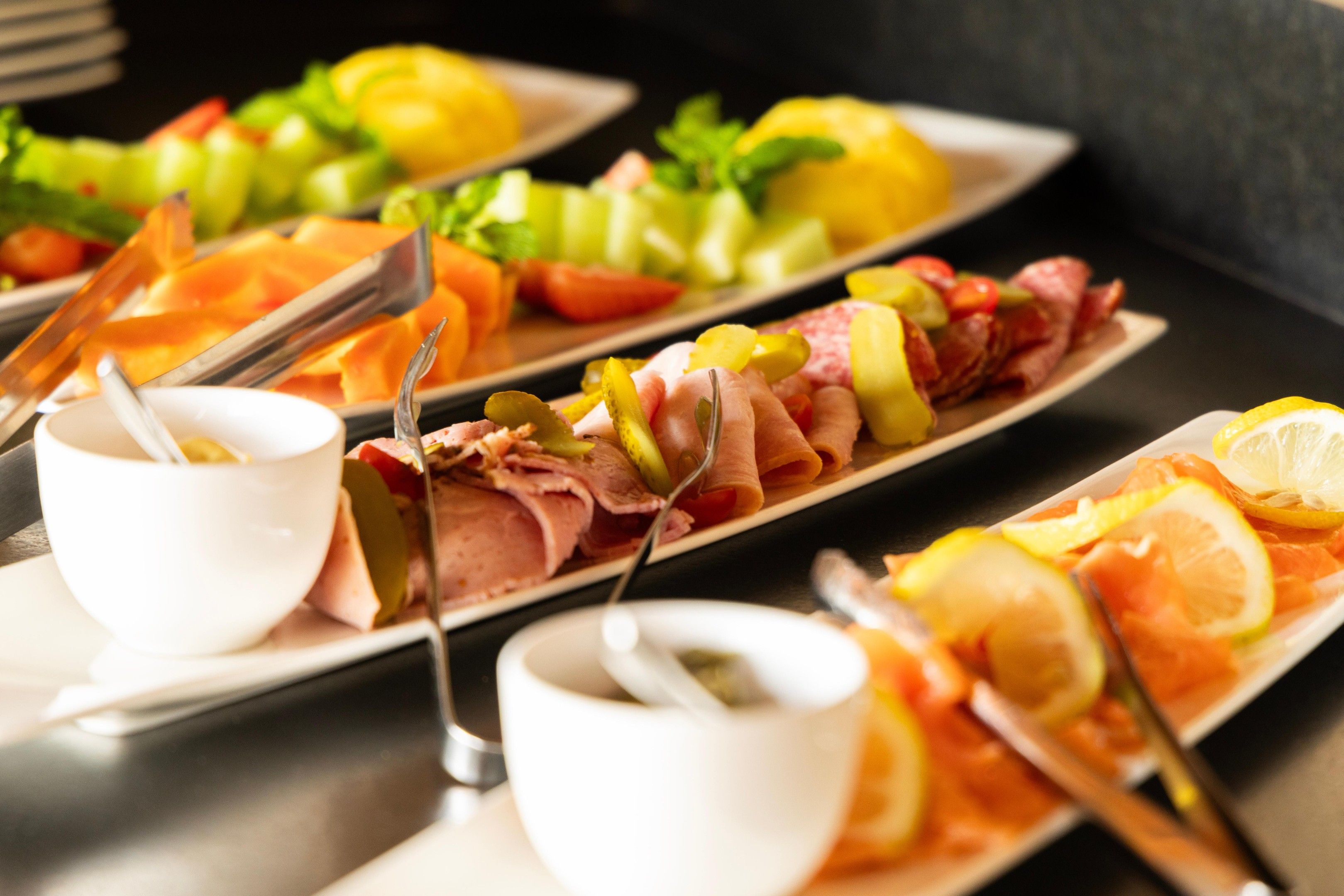 Un buffet proposant une variété de plats, notamment des viandes, des fromages et des fruits.