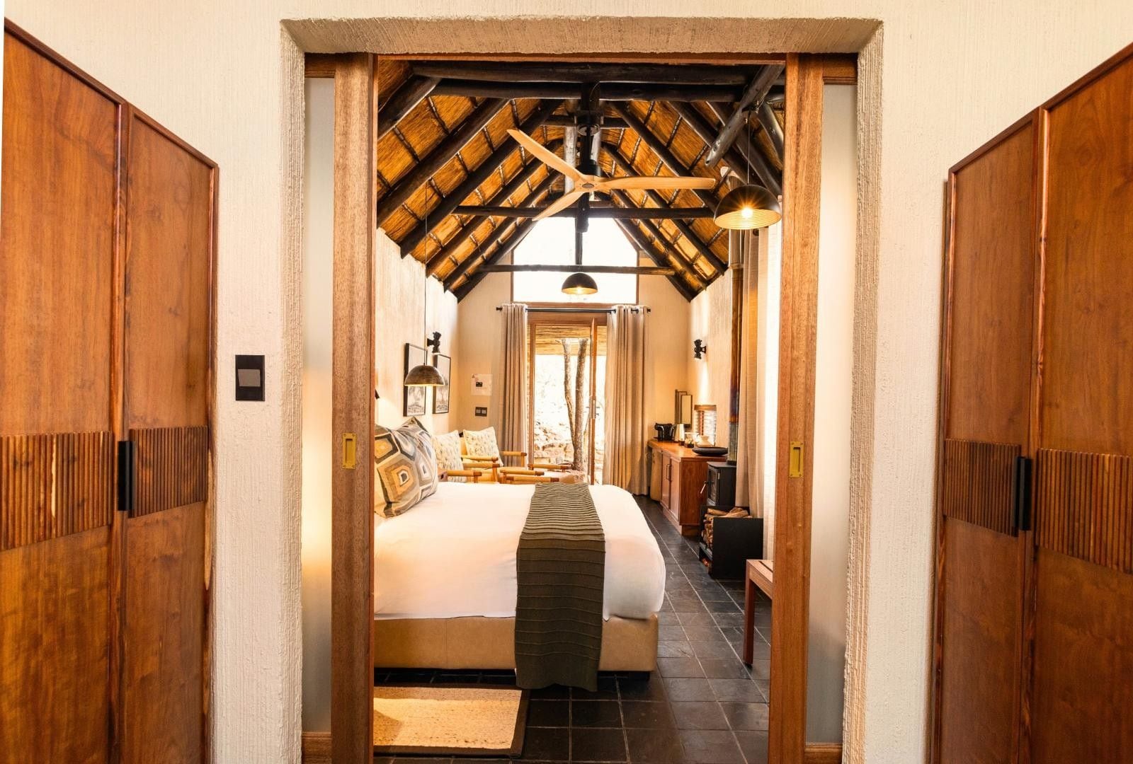 Quarto com cama grande, guarda-roupa de madeira e teto inclinado com vigas aparentes.