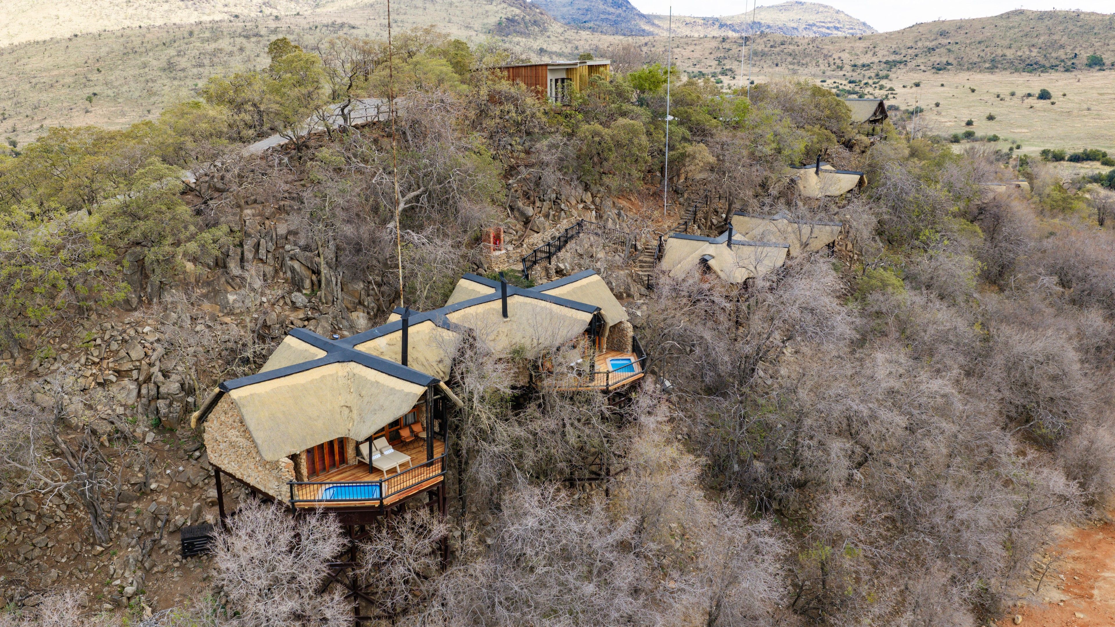 Área isolada e arborizada com diversas acomodações em formato de cúpula, cada uma com um deck de madeira e piscina.