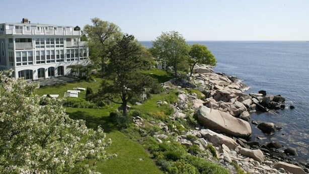 A coastal building with a garden and a rocky shoreline. - The Yankee Clipper Inn (Rockport)