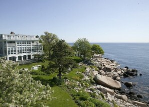 A coastal building with a garden and a rocky shoreline. - The Yankee Clipper Inn (Rockport)