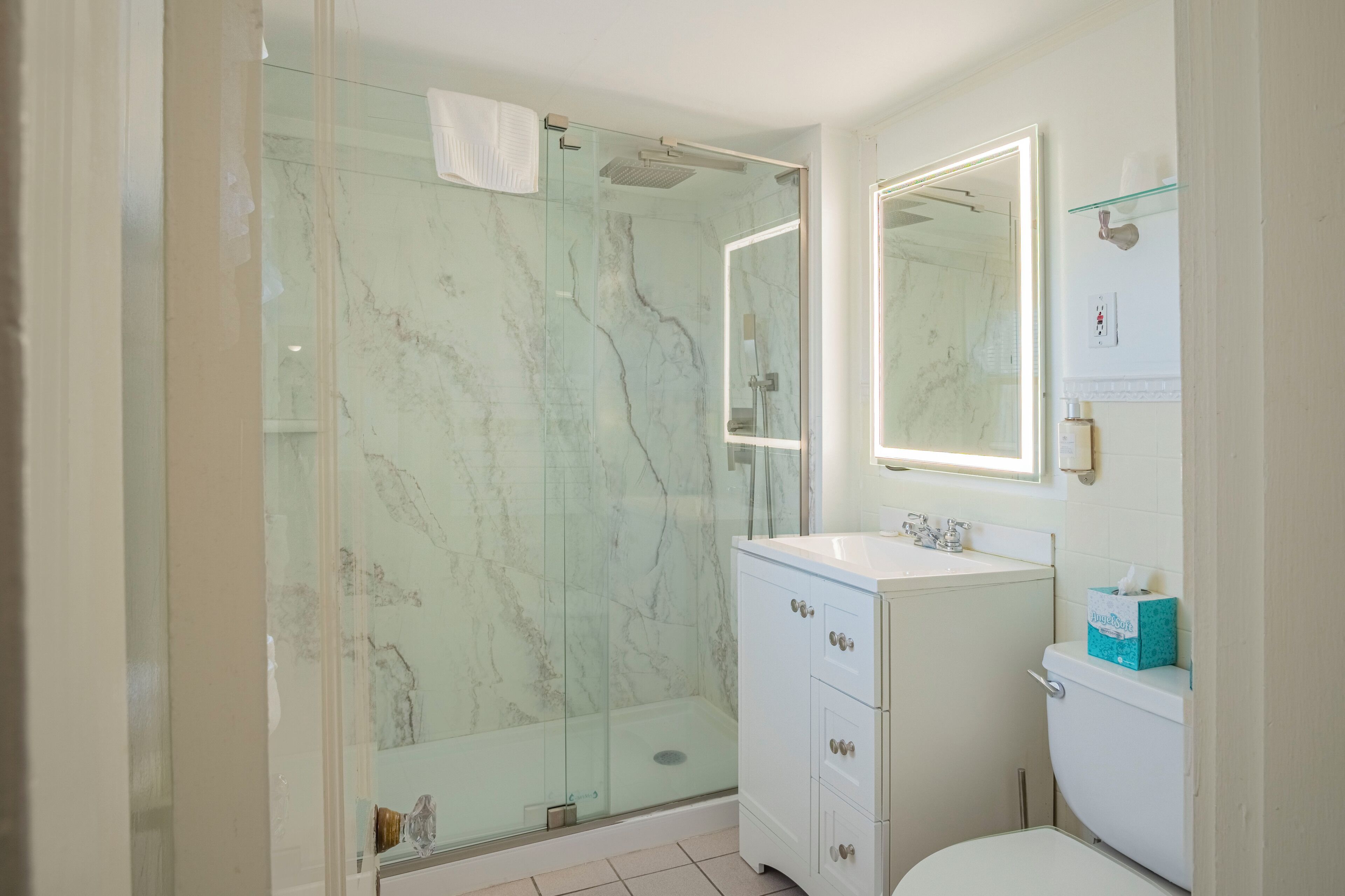 A bathroom with a glass-enclosed shower, a white sink, and a toilet.