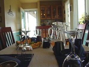 A dining table set with various glassware and a pitcher, surrounded by chairs.