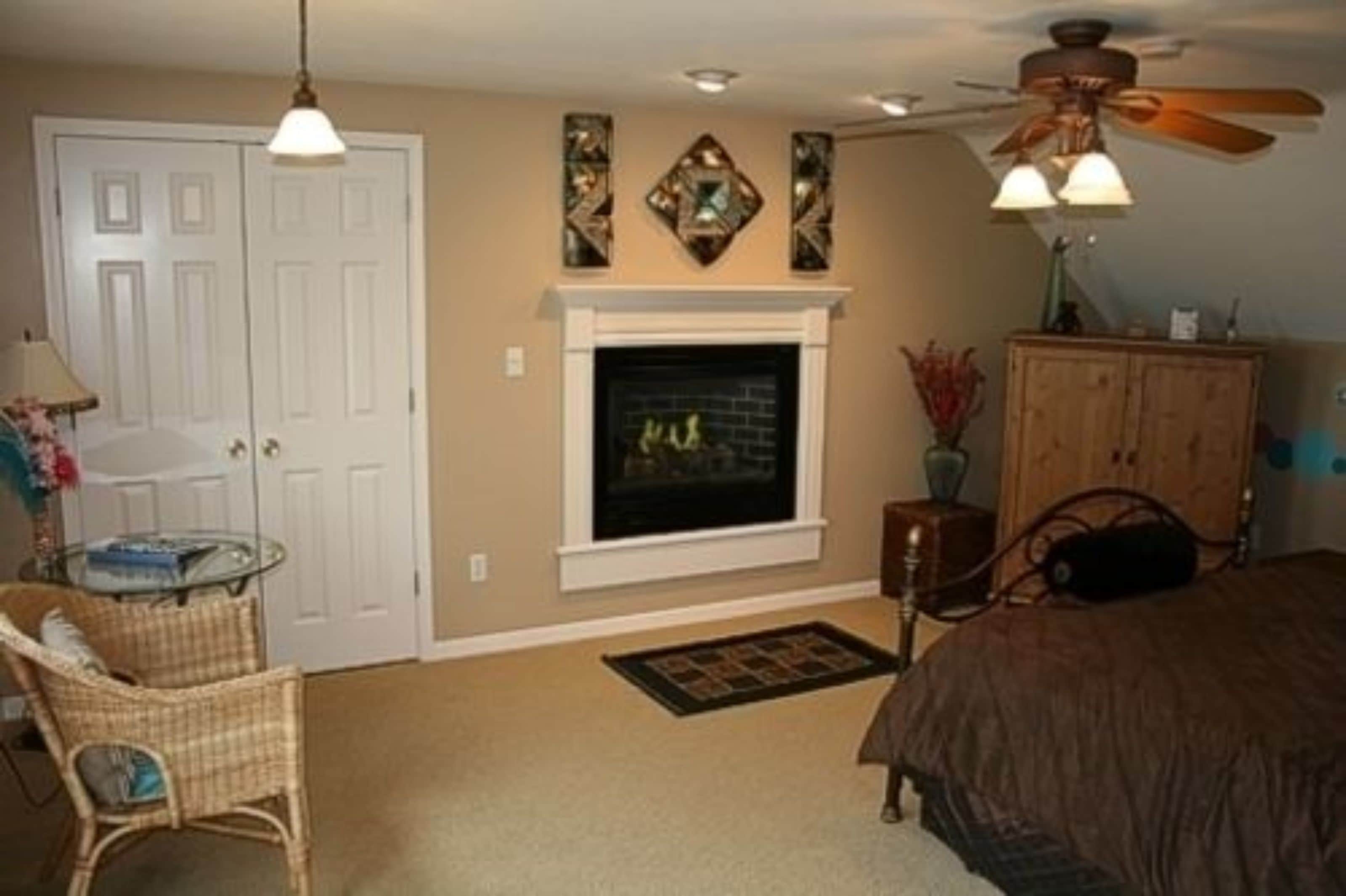 A bedroom with a fireplace, a ceiling fan, and a bed.