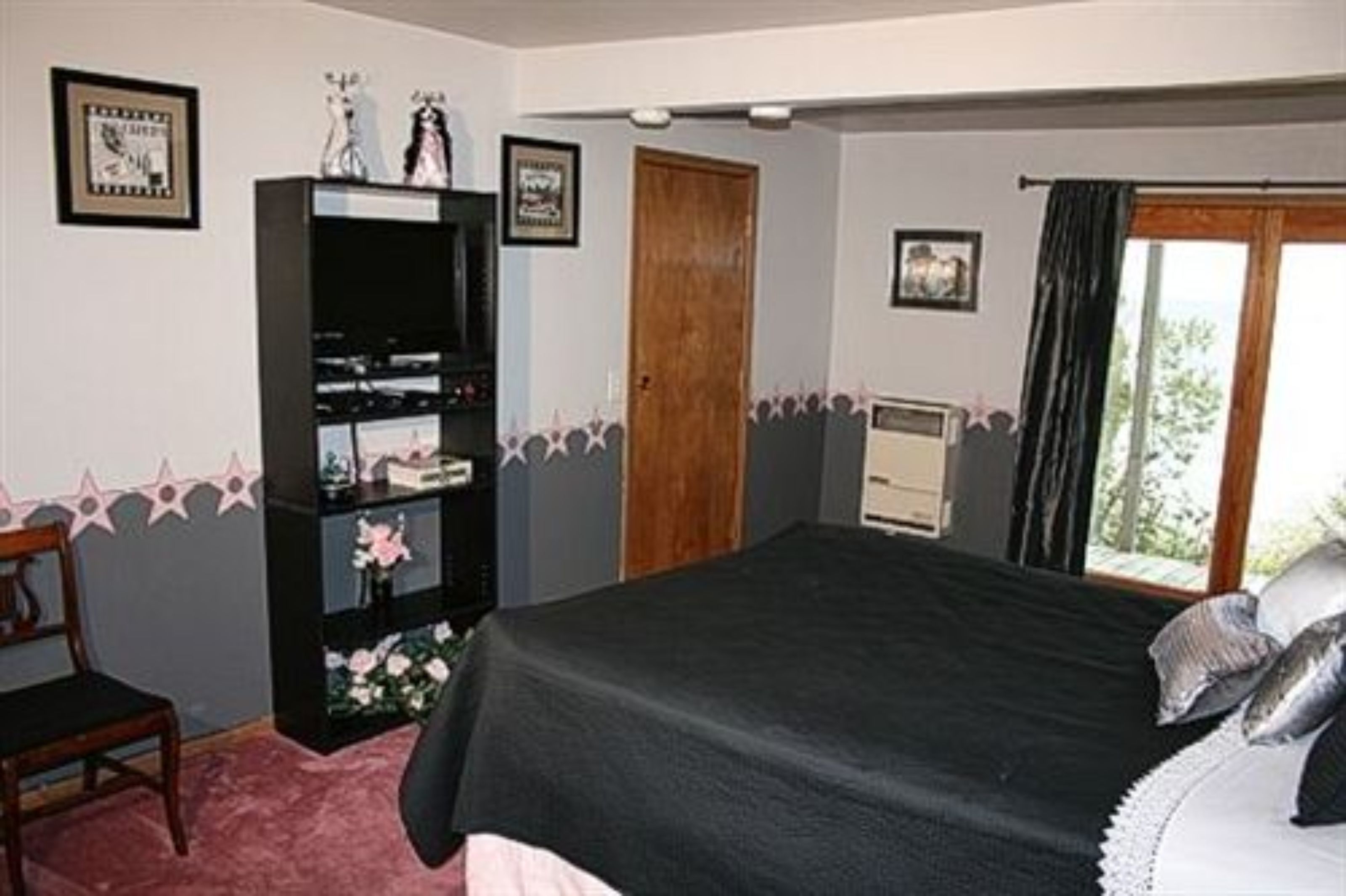 A bedroom with a bed, a wardrobe, a chair, and a window with curtains.
