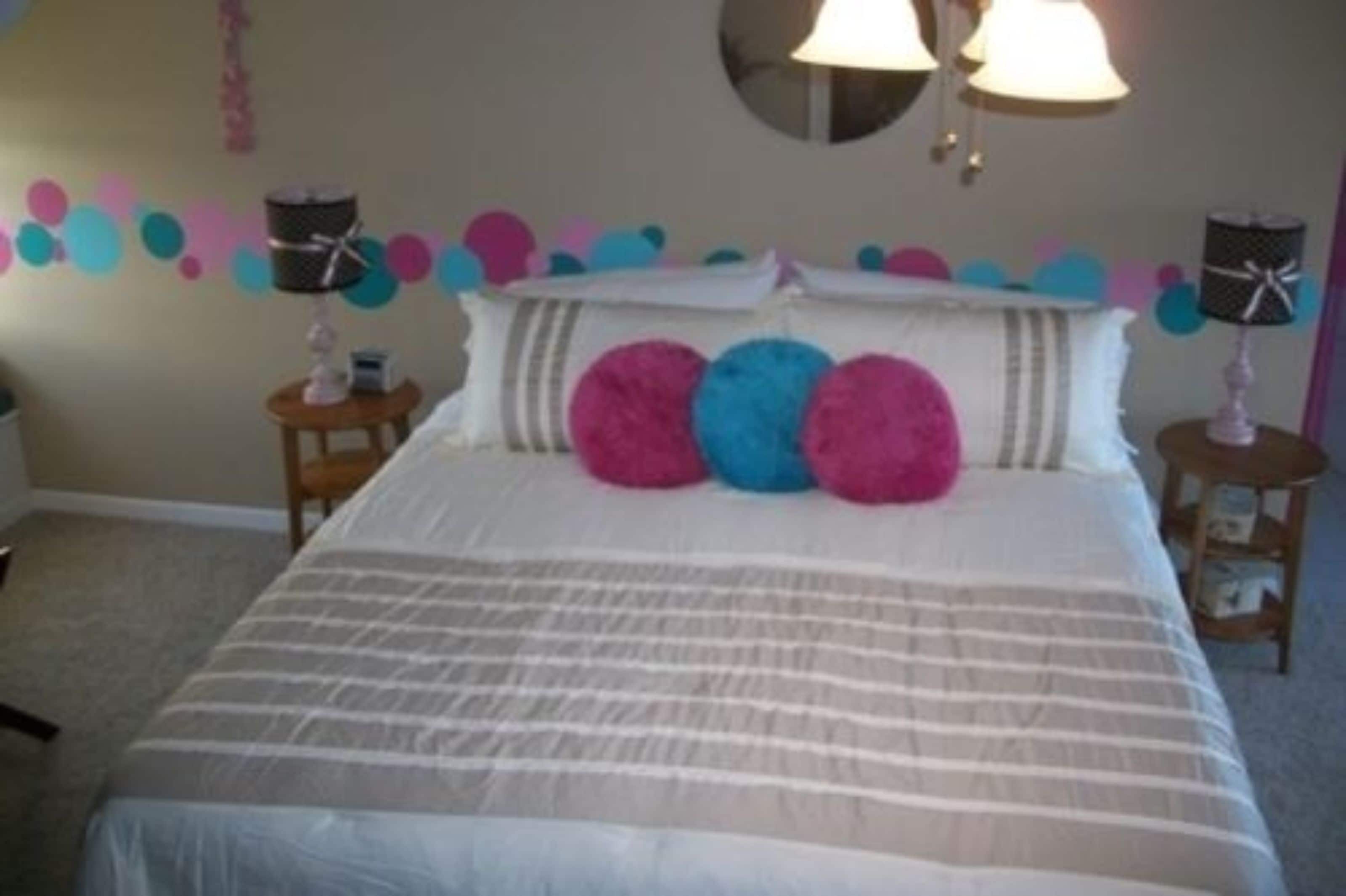 Een slaapkamer met een bed, twee nachtkastjes en een wand met kleurrijke ronde decoraties.