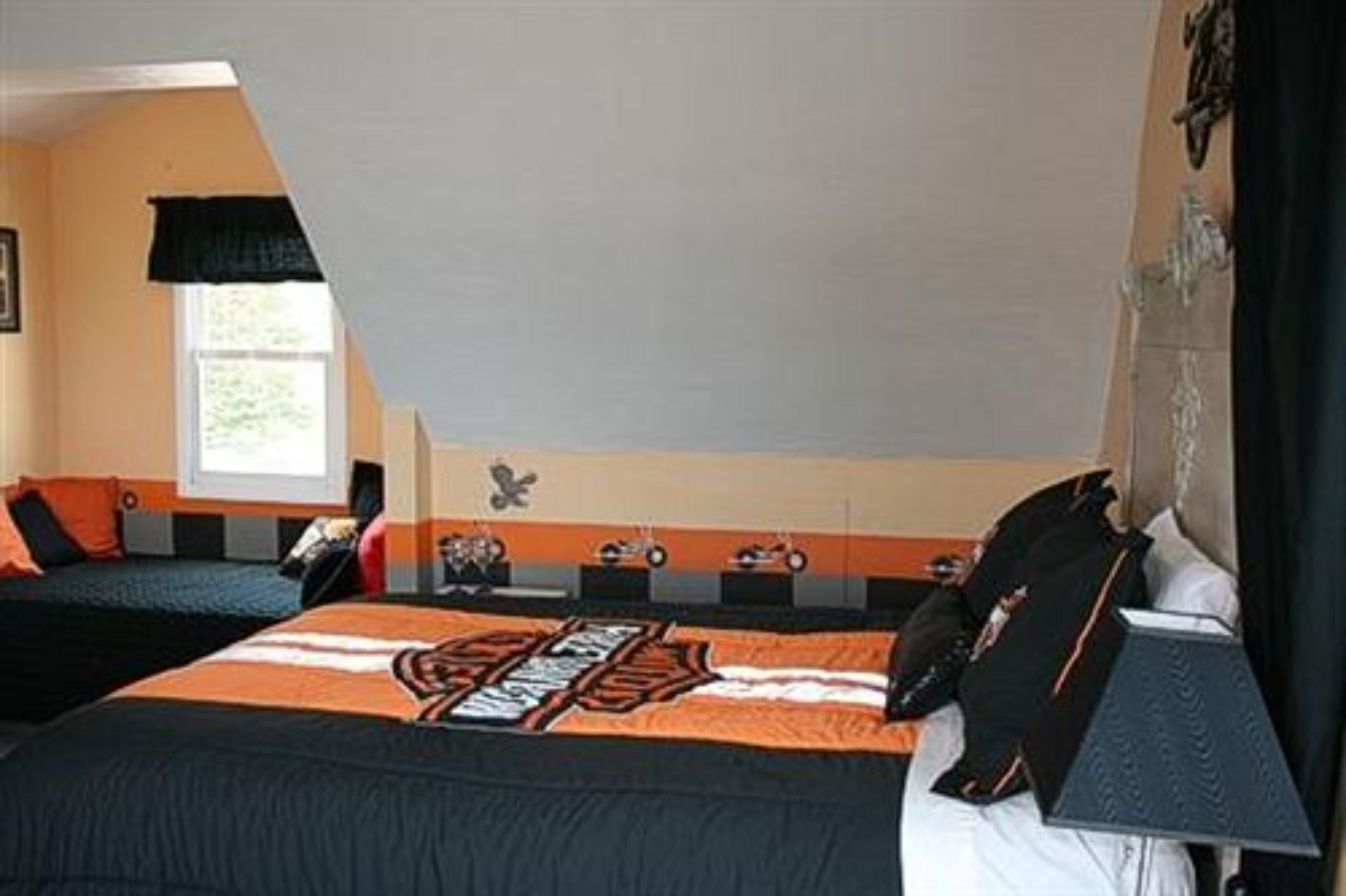 A bedroom with two beds, a window, and a wall with a decorative emblem.