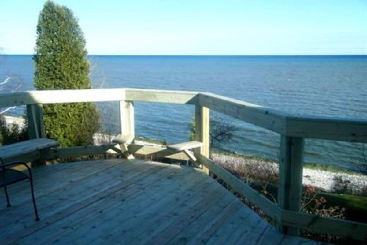 A wooden deck with a bench overlooking a body of water.