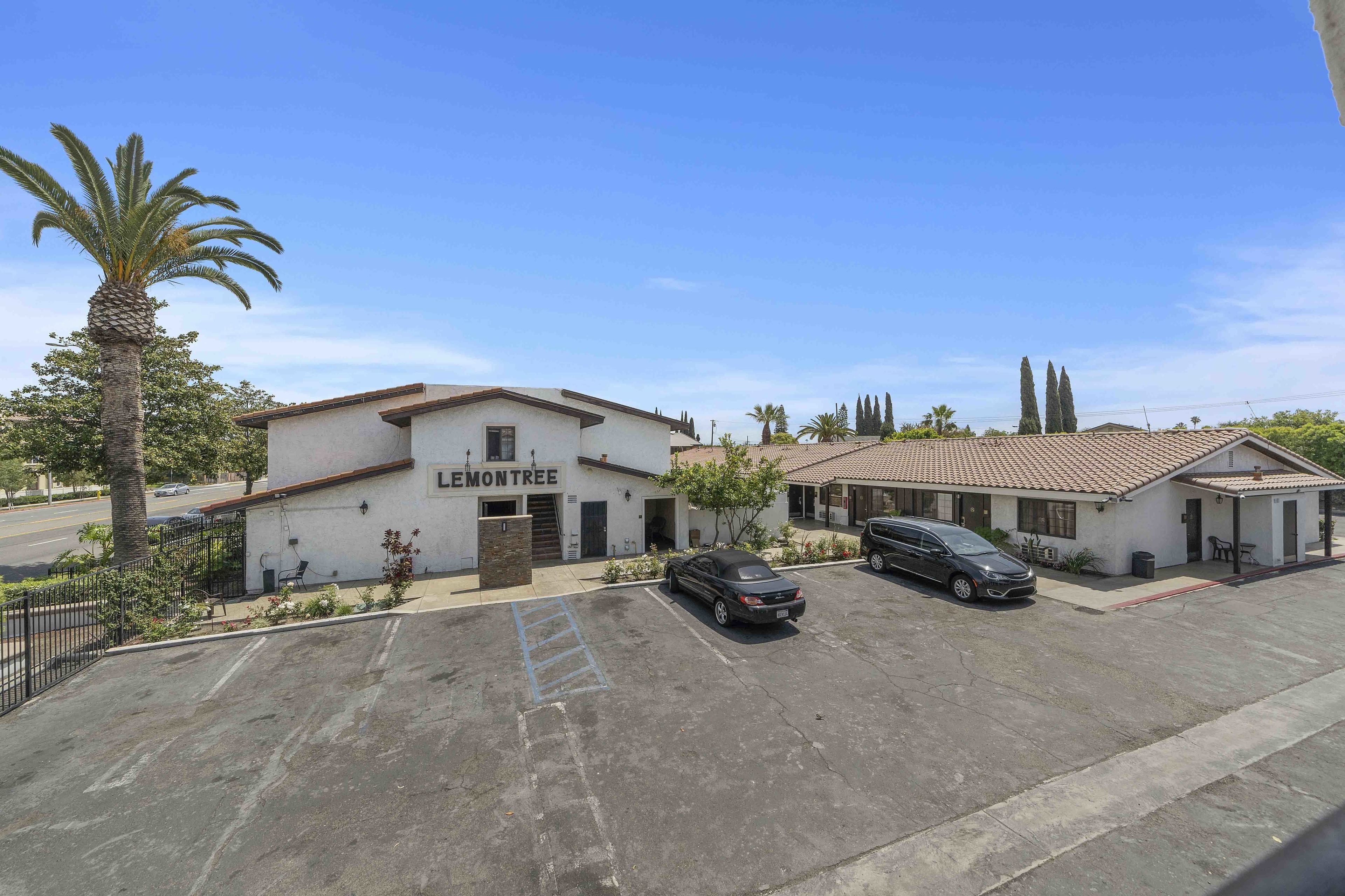 A parking lot with two cars, a building labeled "LEMONTREE," and a palm tree.