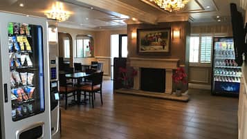 A hotel lobby with a fireplace, dining area, and vending machines.