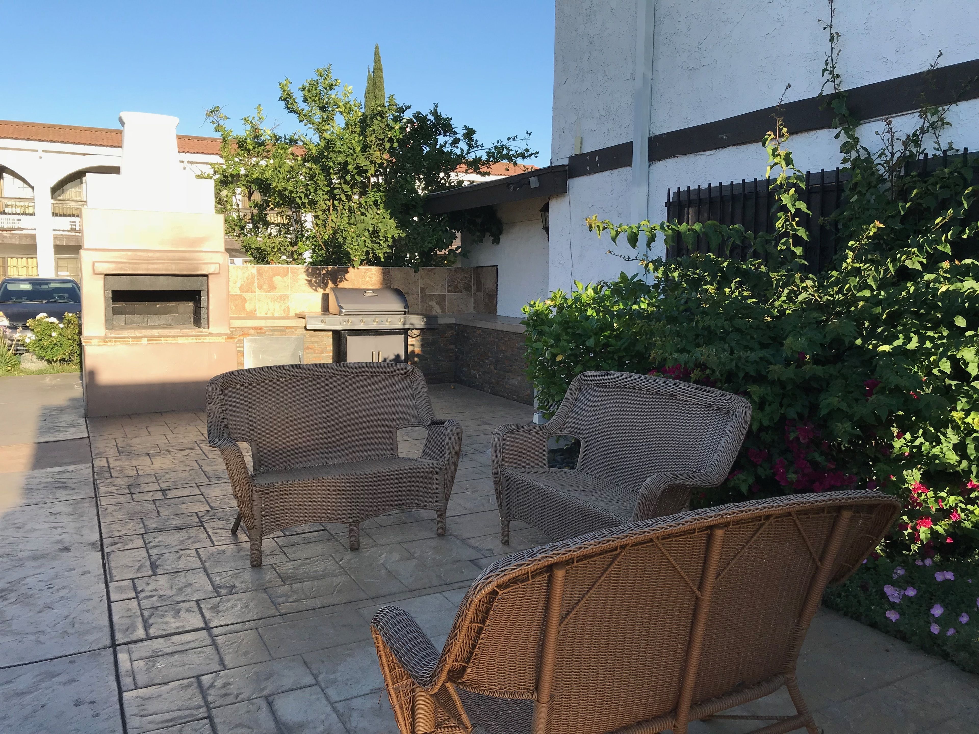An outdoor patio with wicker furniture, a grill, and a pizza oven.