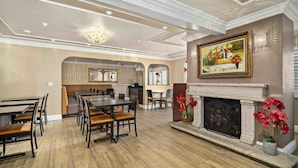 A spacious dining area with a high ceiling, a fireplace, and a painting of flowers. - Lemon Tree Hotel & Suites Anaheim (Anaheim)