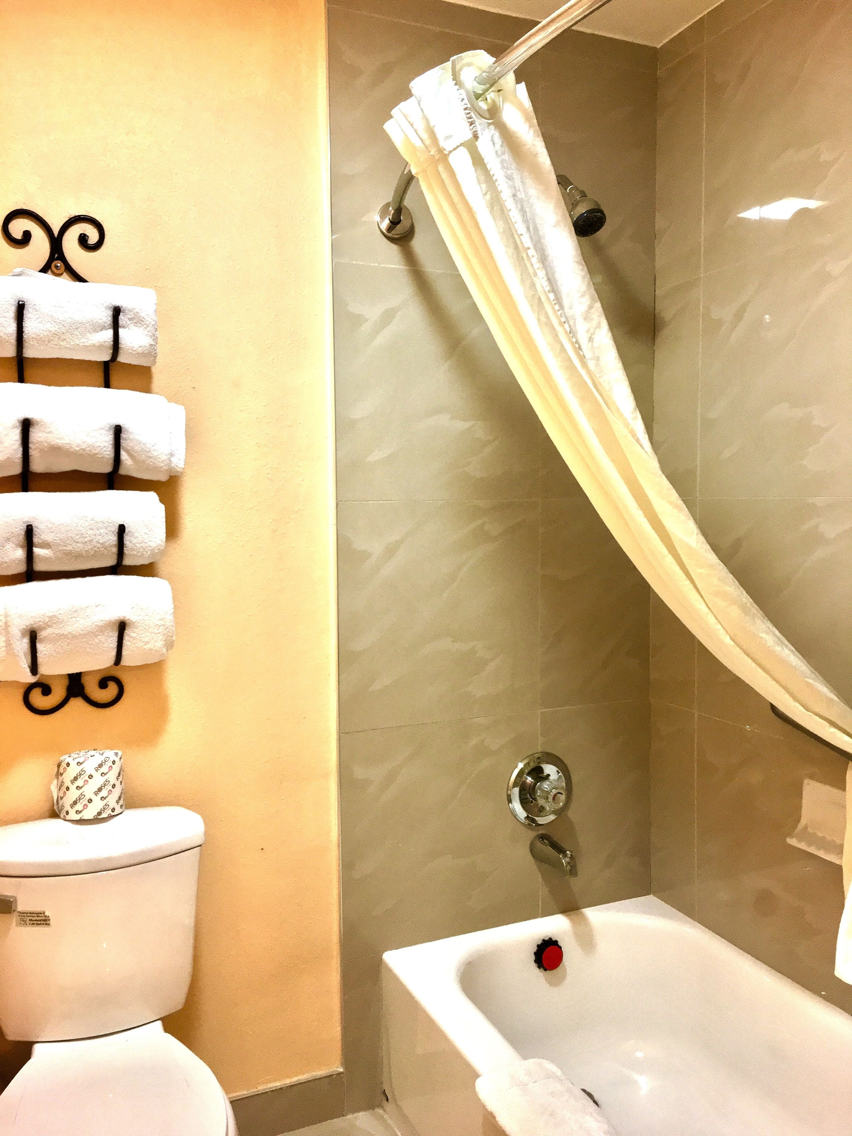 A bathroom with a bathtub, a toilet, and a towel rack with multiple towels.