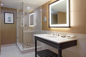 A modern bathroom with a glass-enclosed shower, a large mirror, and a white sink with a black vanity.