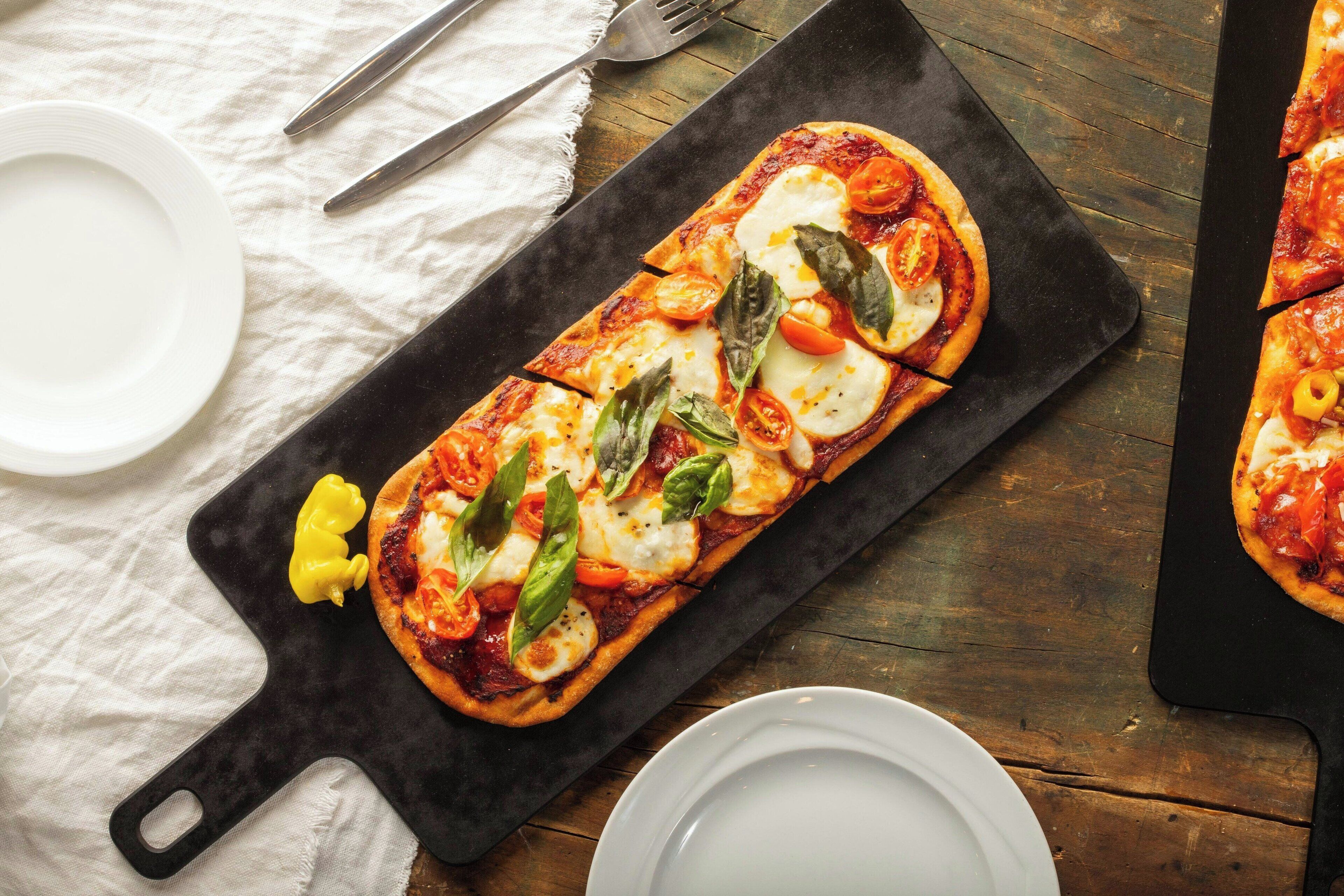 A pizza on a black serving board with a white cloth underneath.