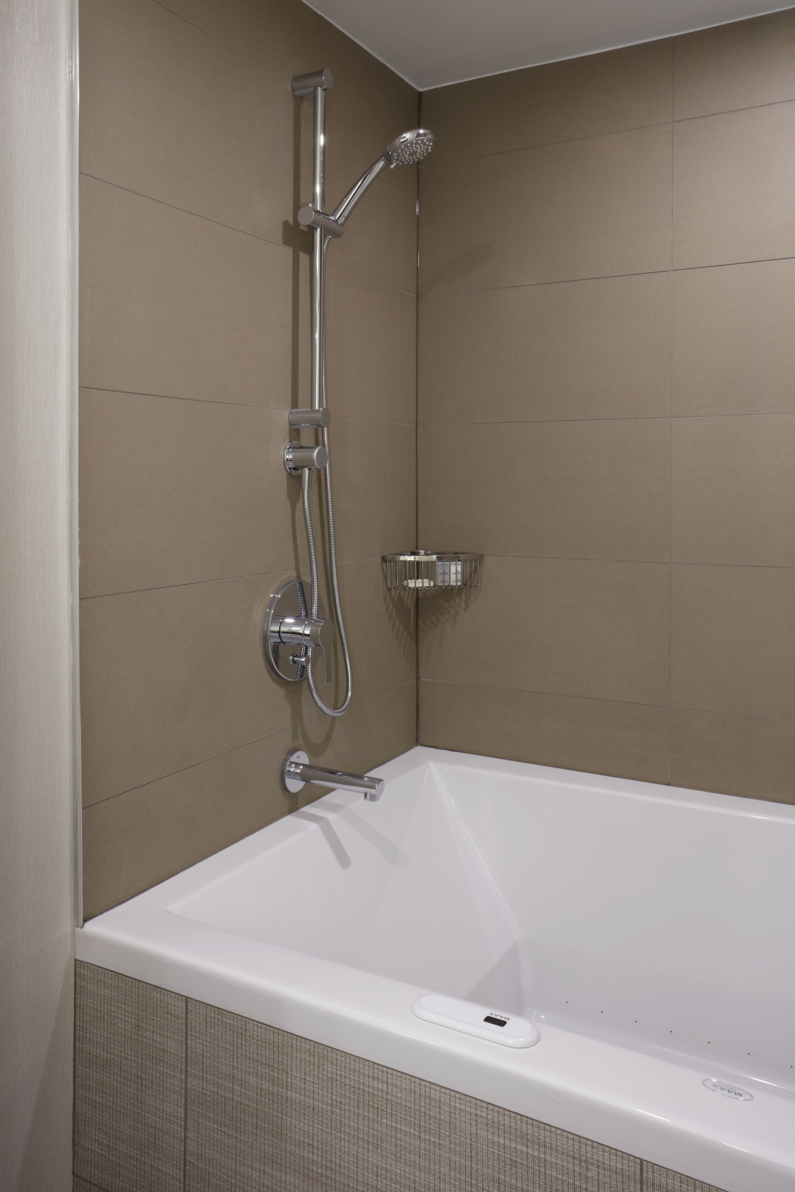 A modern bathroom with a white bathtub, a handheld showerhead, and a wall-mounted faucet.