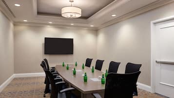 A conference room with a long table, chairs, and a flat-screen TV on the wall.