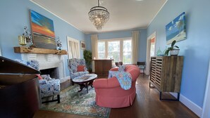 A spacious living room with a fireplace, a chandelier, and a large window.