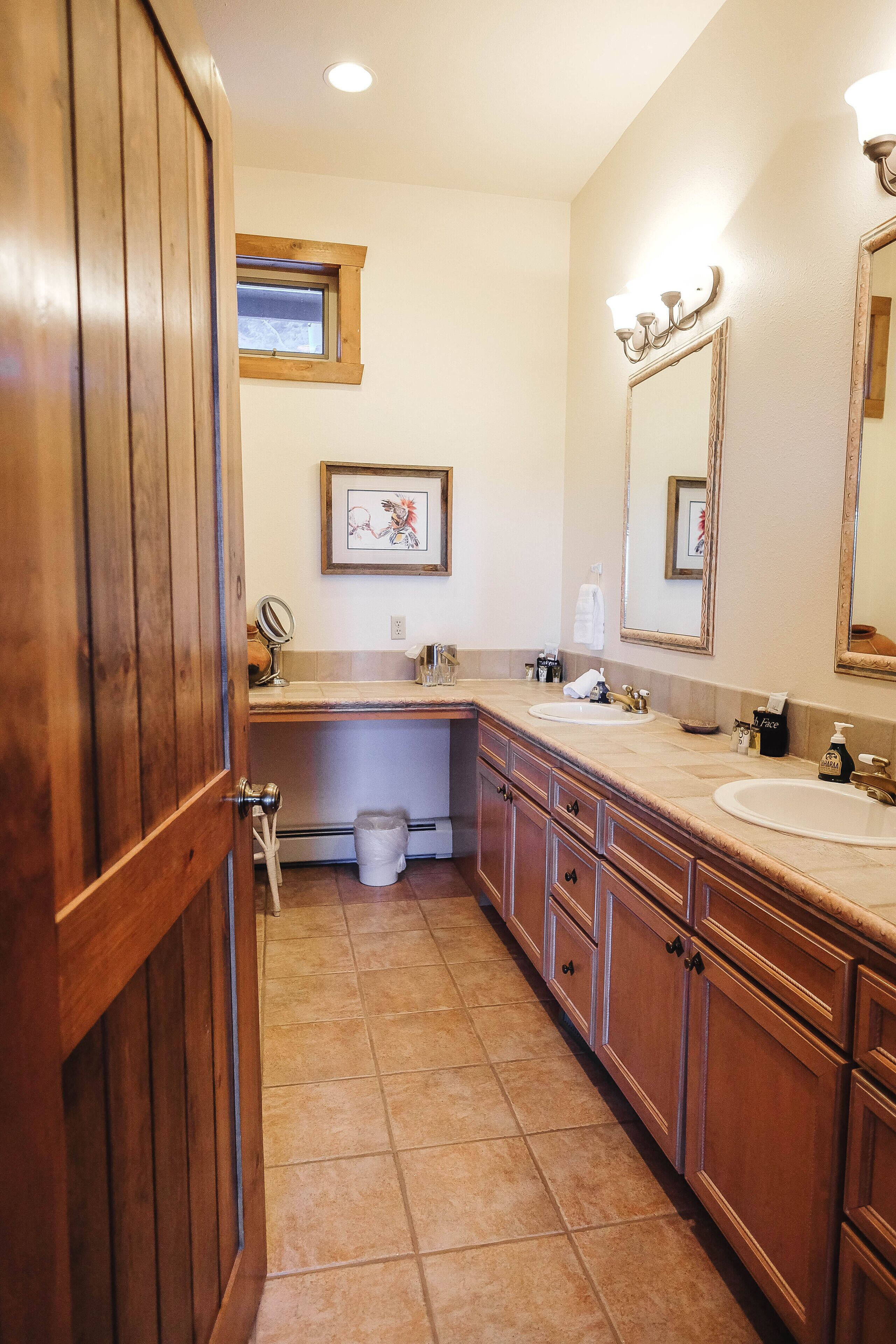 Un bagno con mobili in legno, uno specchio grande e una finestra.