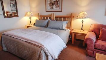 Une chambre à coucher avec un lit, deux tables de chevet, une chaise et un miroir.
