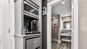 Una kitchenette compacta con microondas, cafetera y refrigerador.