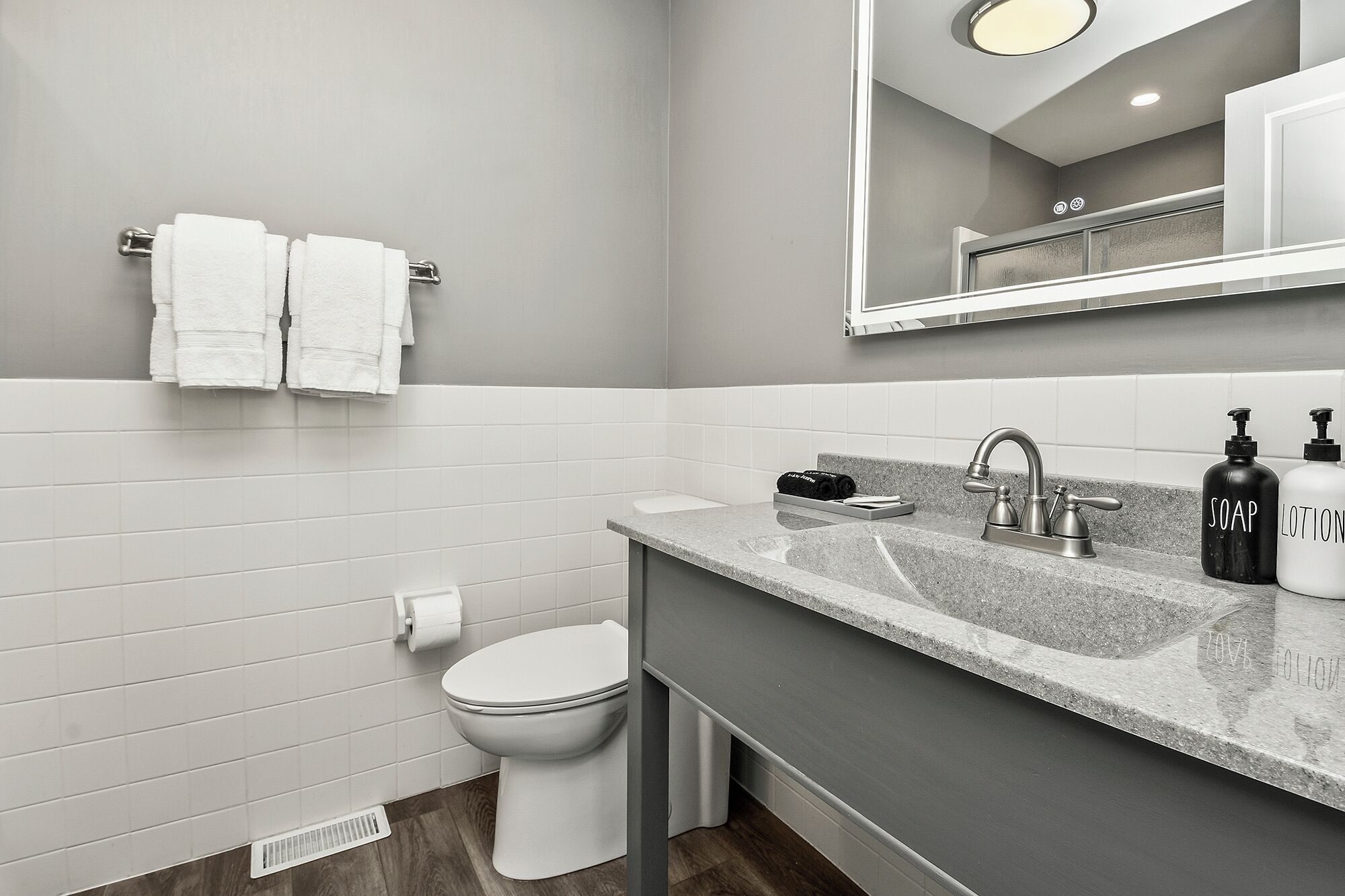 A modern bathroom with a toilet, sink, and mirror.