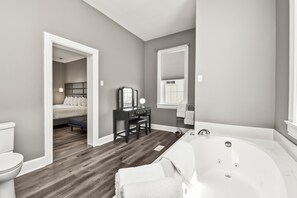 A modern bathroom with a wooden floor, a white bathtub, and a vanity with a mirror.