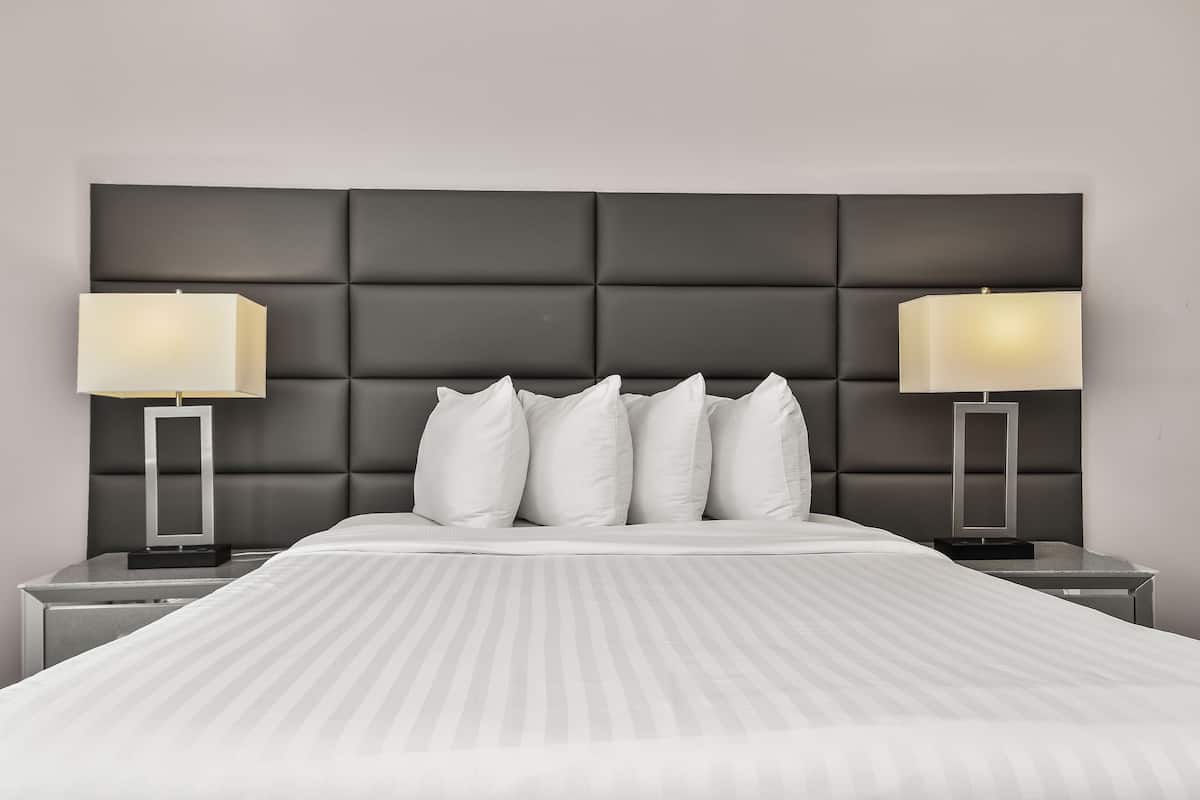 A neatly made bed with a striped bedspread, two bedside tables with lamps, and a dark headboard.