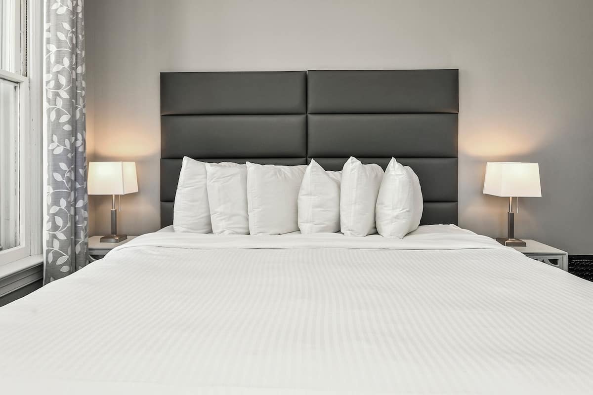 A neatly made bed with a dark headboard, white bedding, and two bedside lamps.