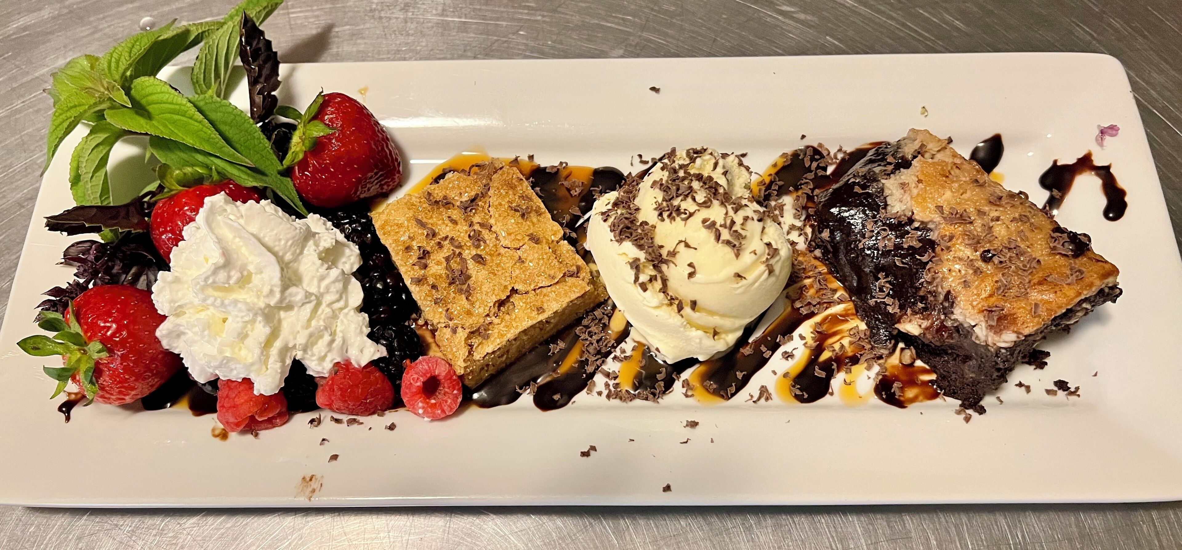 A dessert plate with strawberries, whipped cream, chocolate cake, and ice cream.