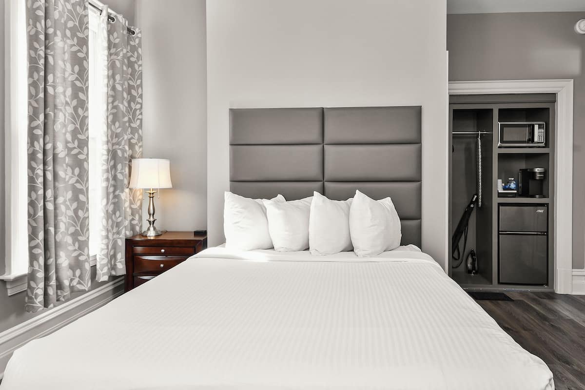 A hotel room with a large bed, a nightstand with a lamp, a wardrobe, and a shower area.