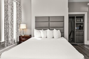 A hotel room with a large bed, a nightstand with a lamp, a wardrobe, and a shower area.