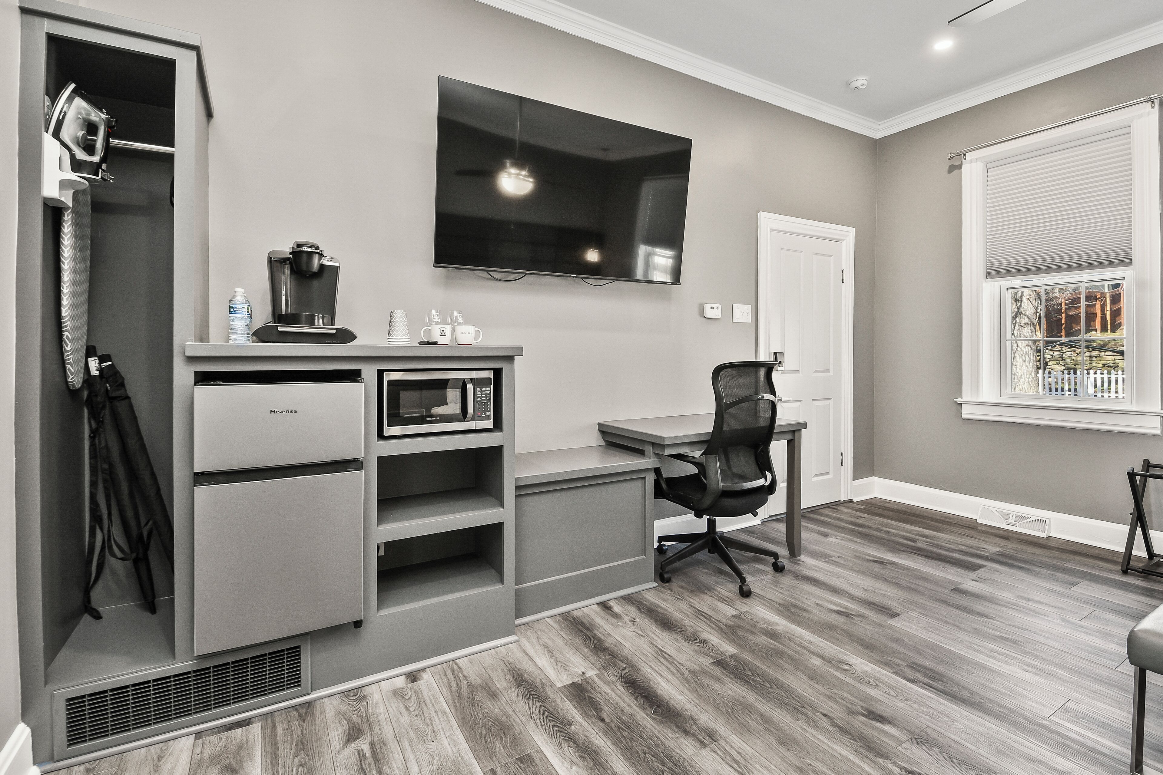 A modern kitchen with a built-in microwave, coffee maker, and a flat-screen TV mounted on the wall.