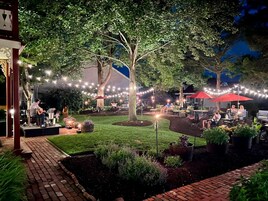 Un patio al aire libre con luces colgantes, asientos y plantas en macetas.